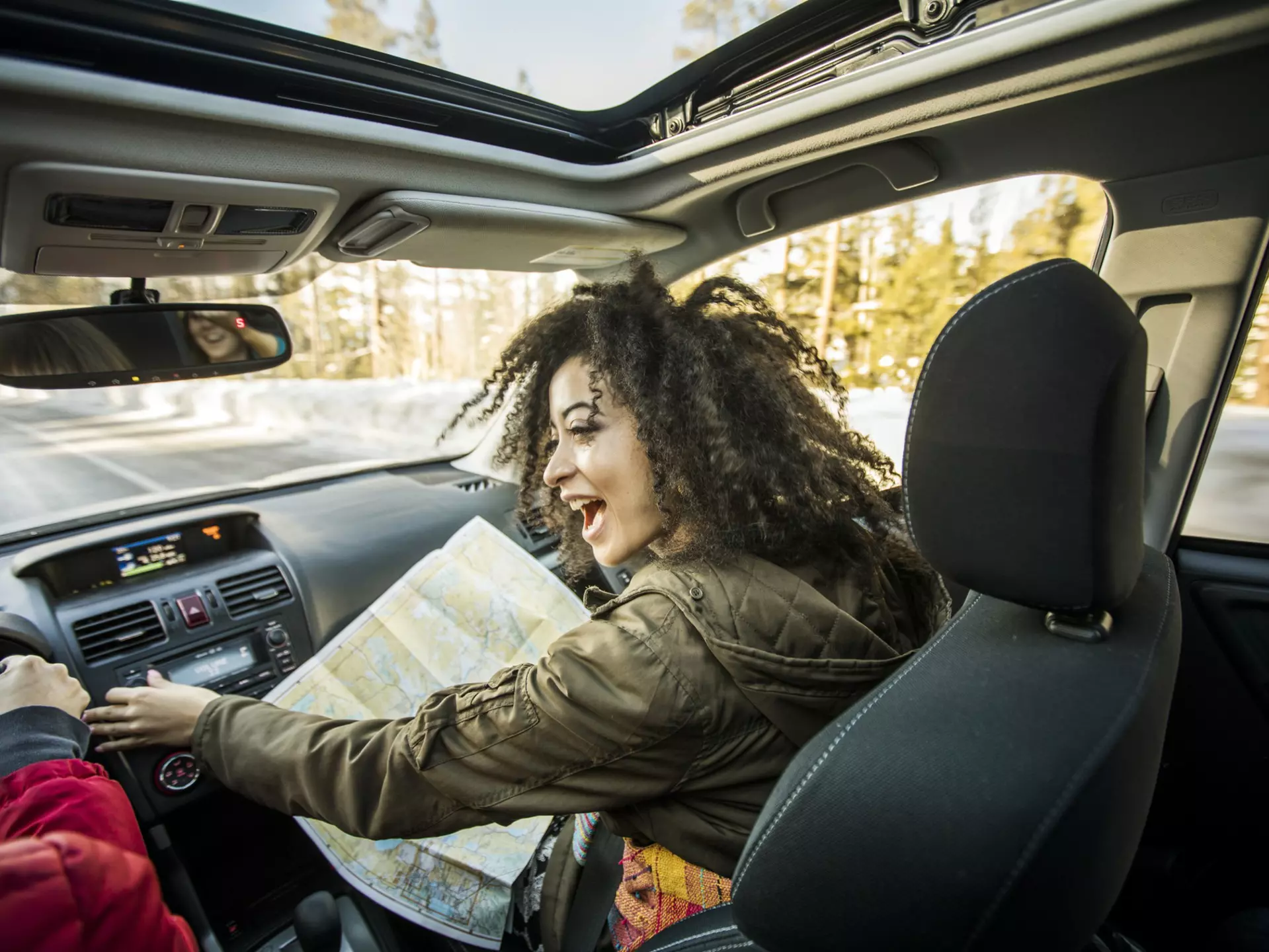 Woman driving car, friend in passenger seat looking at map