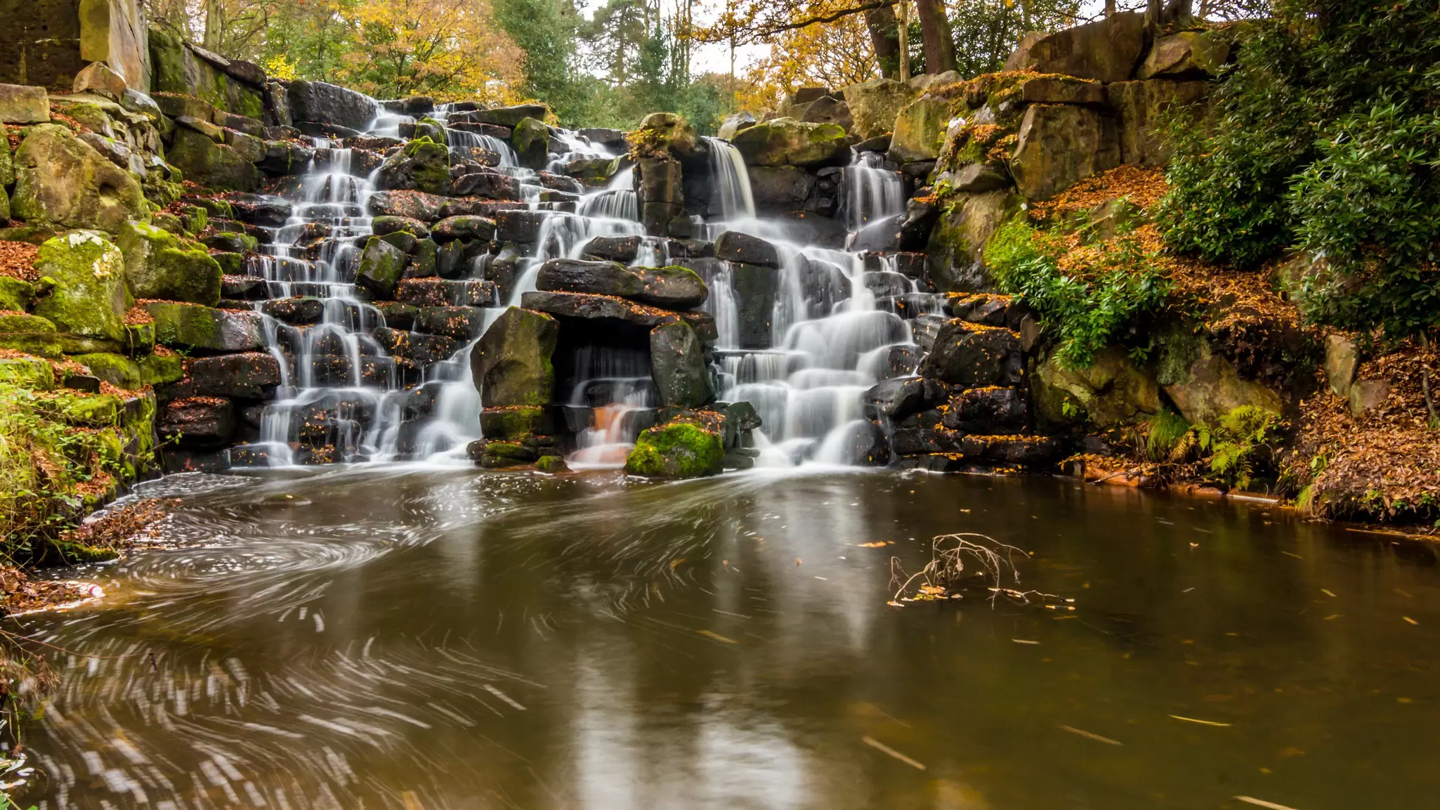 A waterfall cascading over rocks into a dark swirling pool