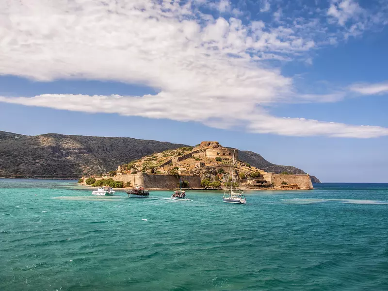 Boats sail in front of a Venetian fortress on an island