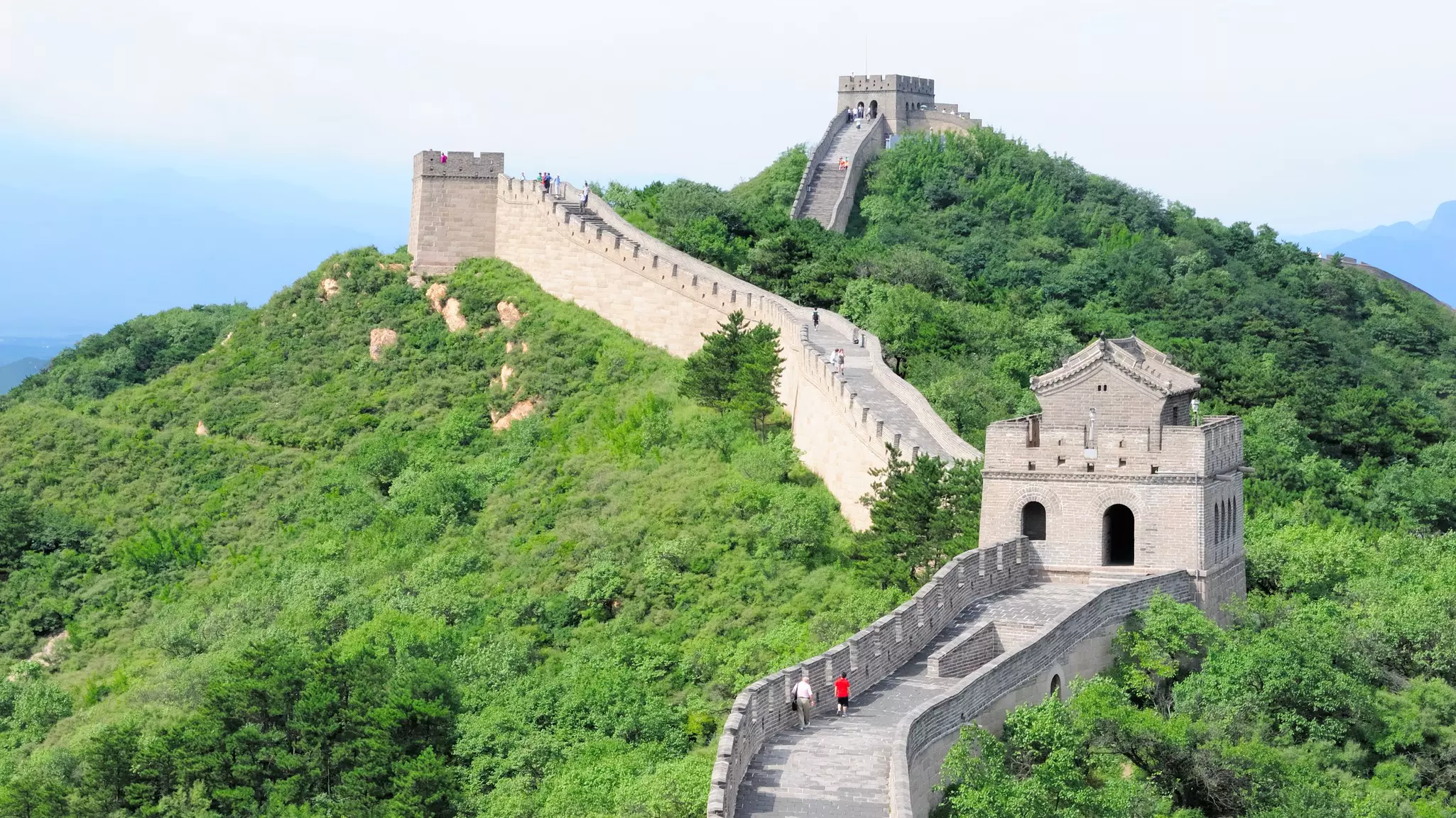 A stone wall on a mountain with a pathway along the top.