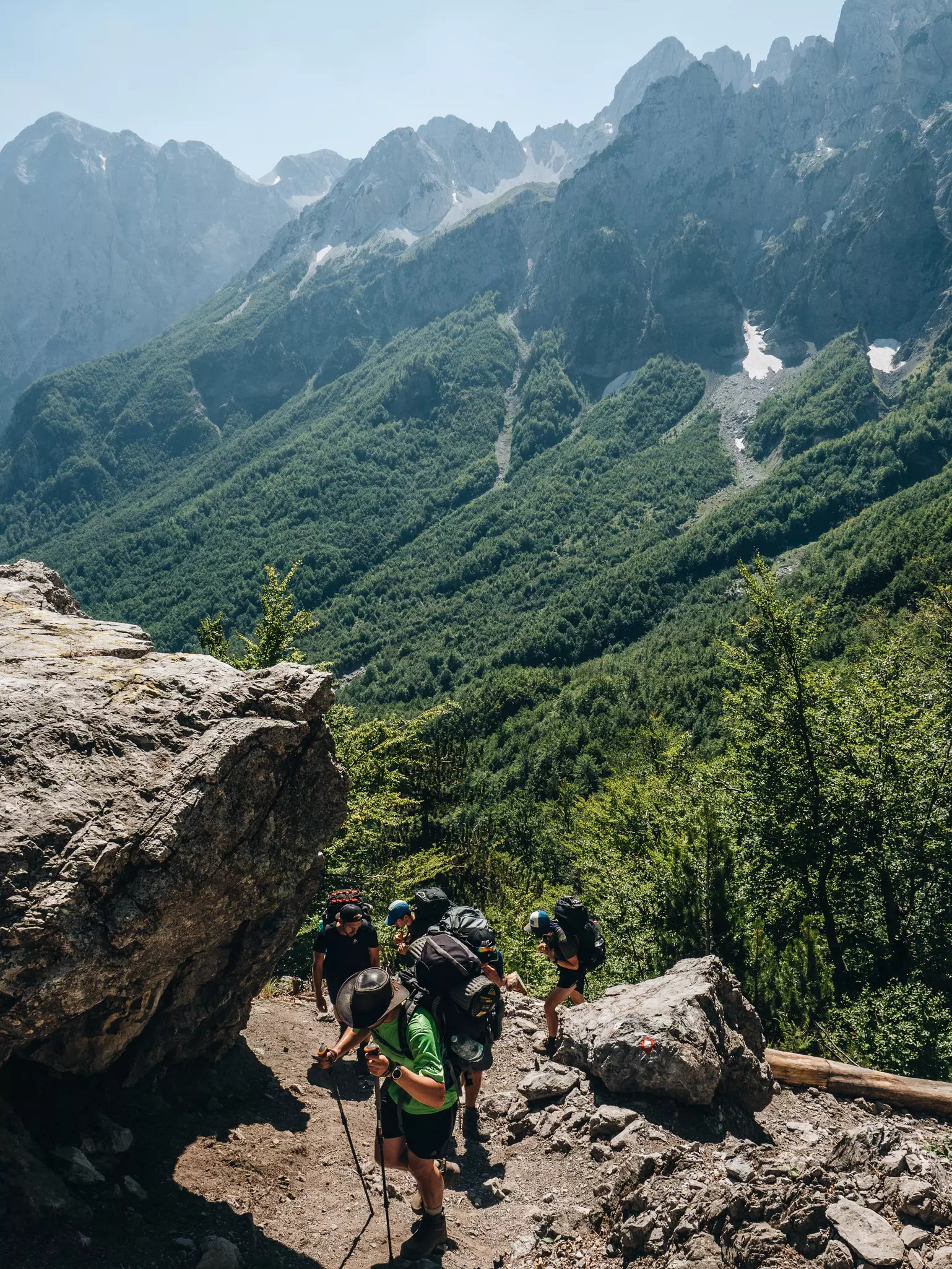 Family hiking in a group in the mountains of Albania with hats and backpacks