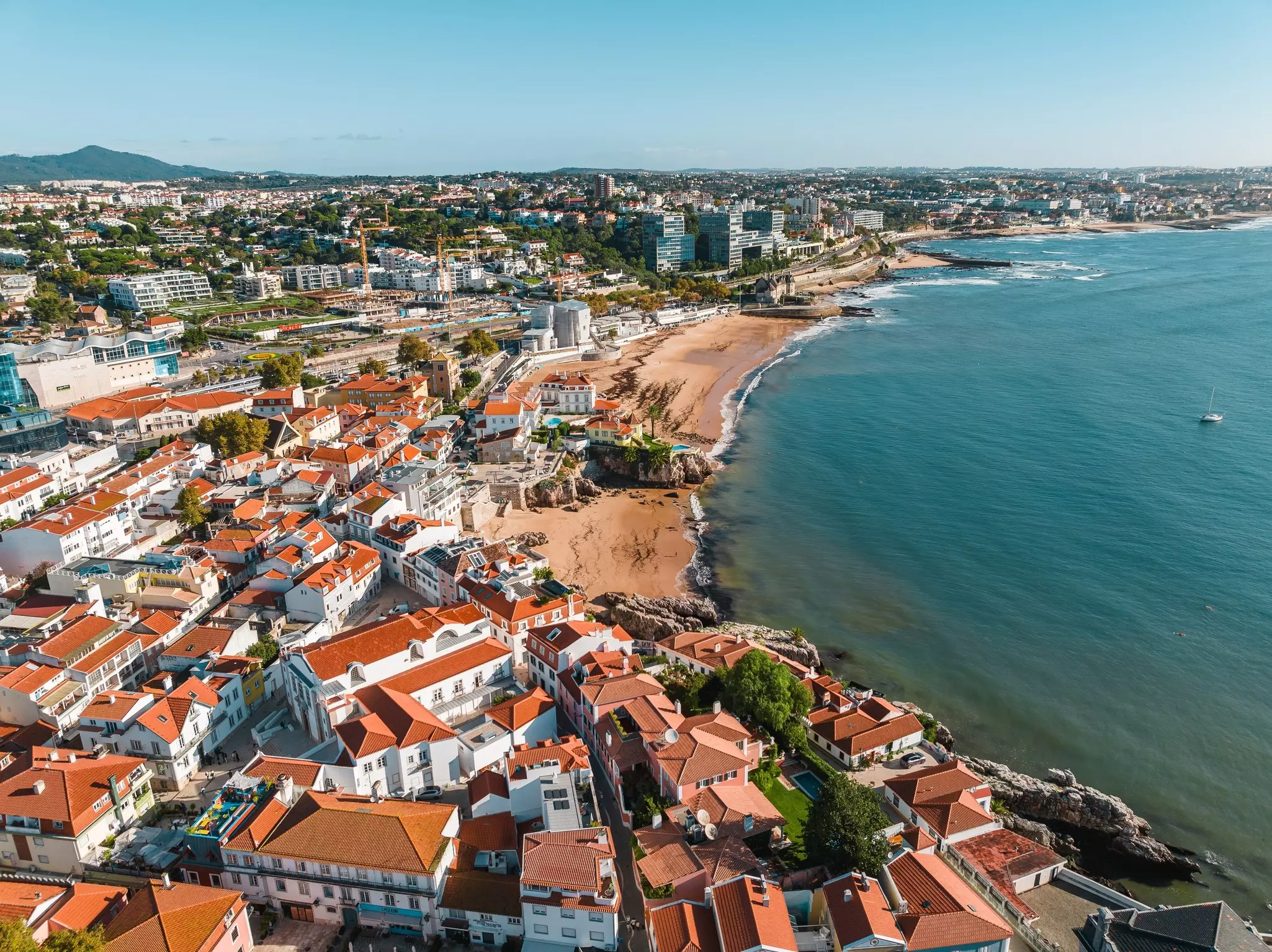 An aerial view of a seafront town in Portugal with red-roofed buildings and large stretches of beach.