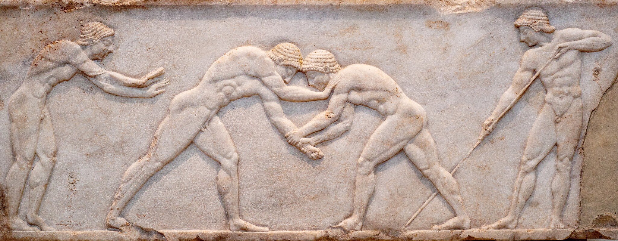 Ancient bas-relief on grave stele in Kerameikos with scene from Palaestra - wrestlers in action. On the left an athlete is ready to jump, on the right another one prepairing the pit. Athens, Greece; Shutterstock ID 1745203673; your: Erin Lenczycki...