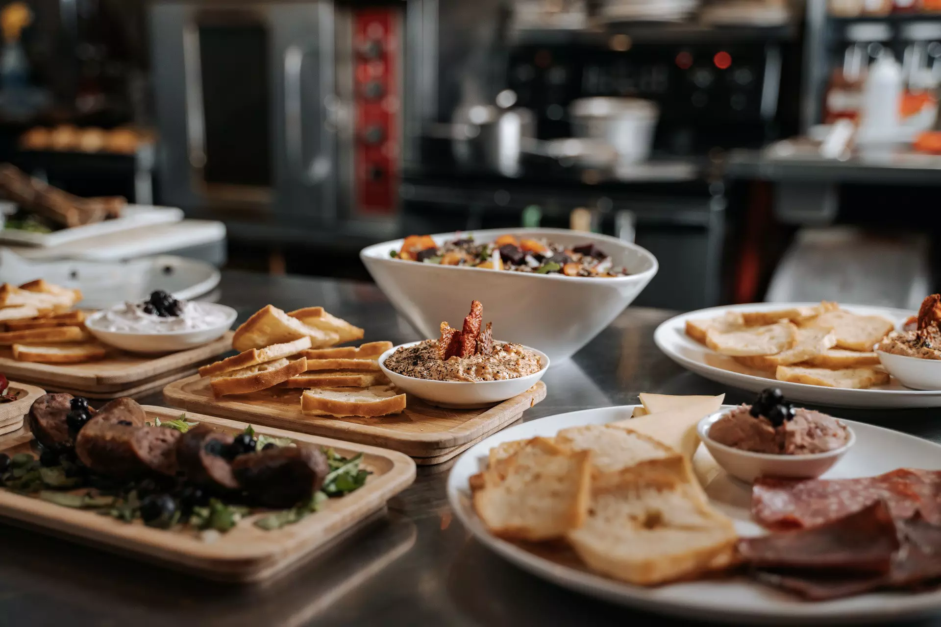 A table loaded with sharing plates of bread, dips and salad.