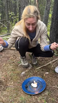 A woman lights a fire on a blue plate.