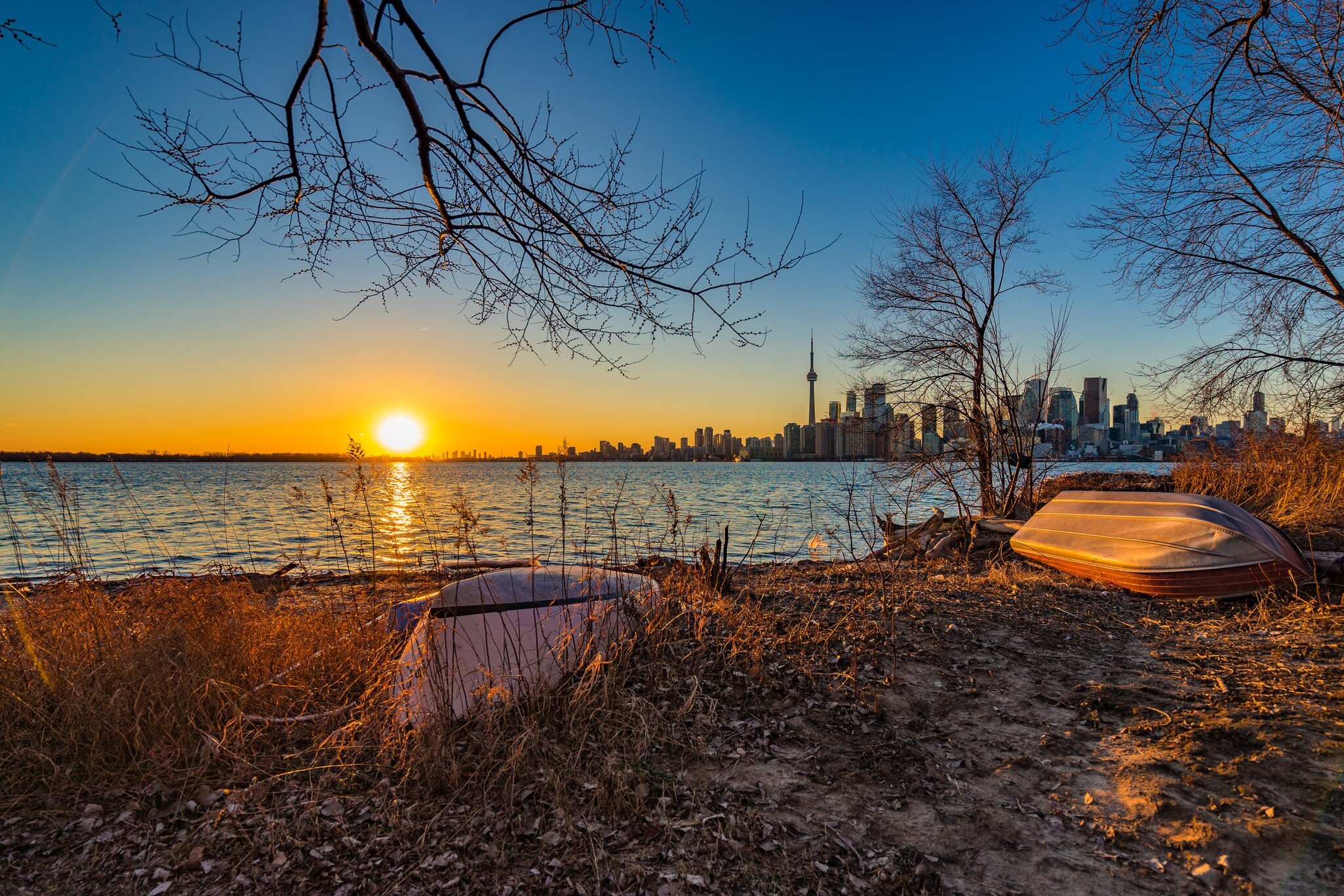 A sunset with a city skyline in the background, boats in the foreground