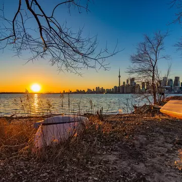 A sunset with a city skyline in the background, boats in the foreground