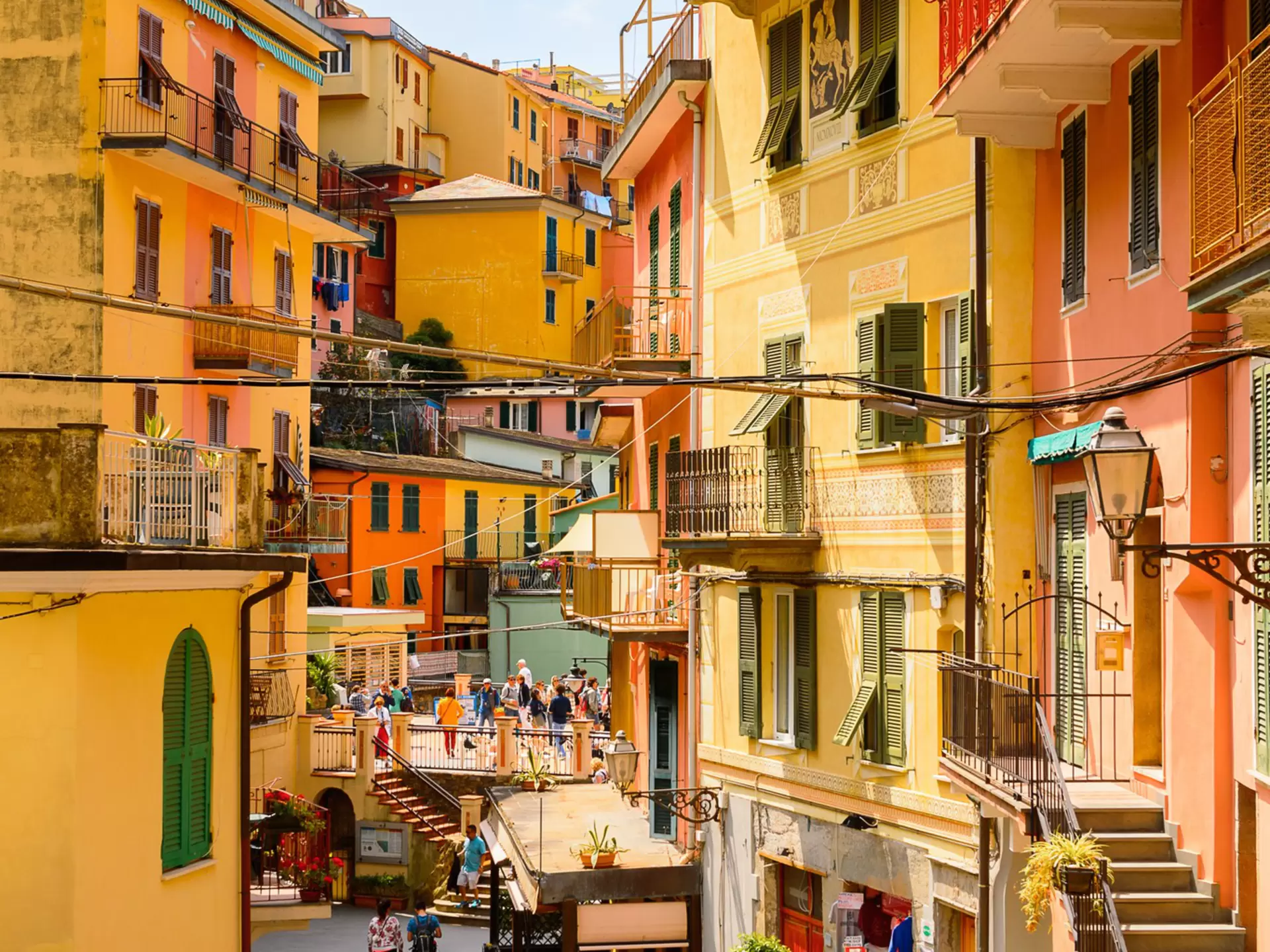 Tourists walking along a village street lined with yellow and orange colored houses