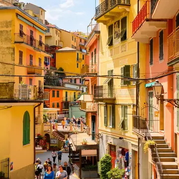 Tourists walking along a village street lined with yellow and orange colored houses
