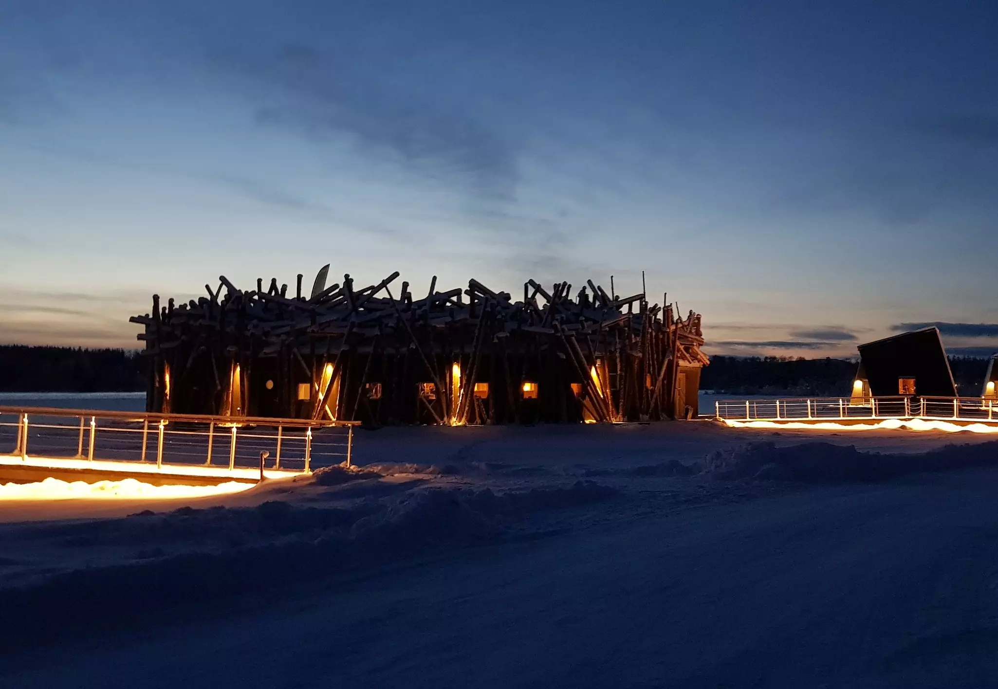A huge round wooden structure at night surrounded by ice and snow