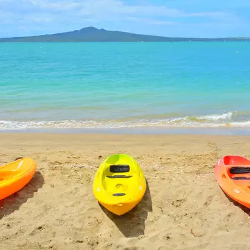 Auckland  New Zealand - November 21 2020: View of three colourful kayaks at Mission Bay with Rangitoto Island in background  License Type: media  Download Time: 2022-04-28T10:23:46.000Z  User: aniabartoszek  Is Editorial: Yes  purchase_order: