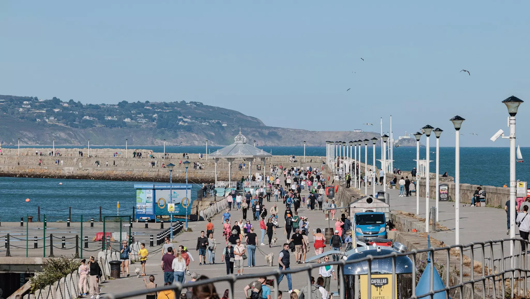 A wide view of people walking on a seaside pier on a summer afternoon