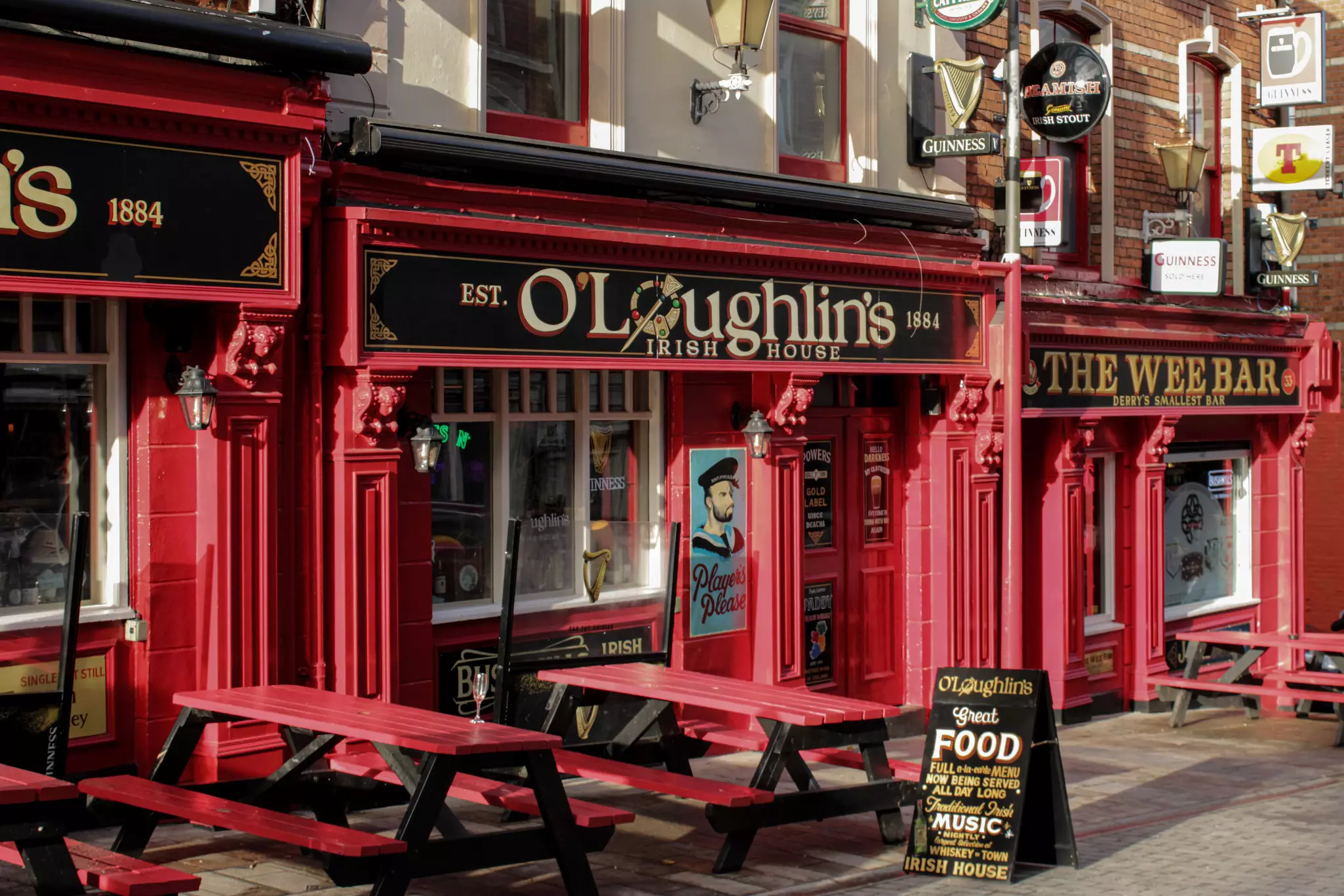 A red facade of a pub; the black and gold sign says "O'Loughlins Irish House"