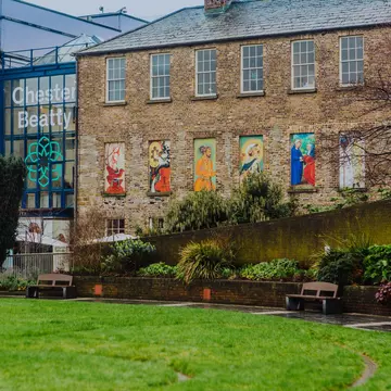 A large brick building at the edge of a green lawn