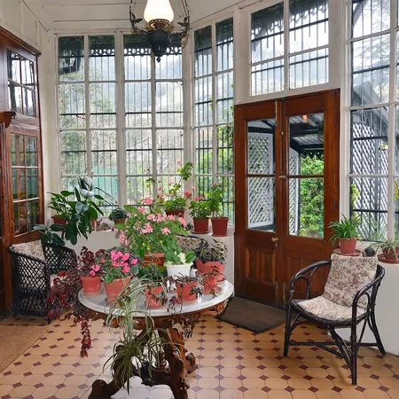 A conservatory with flower-filled pots on a central table.