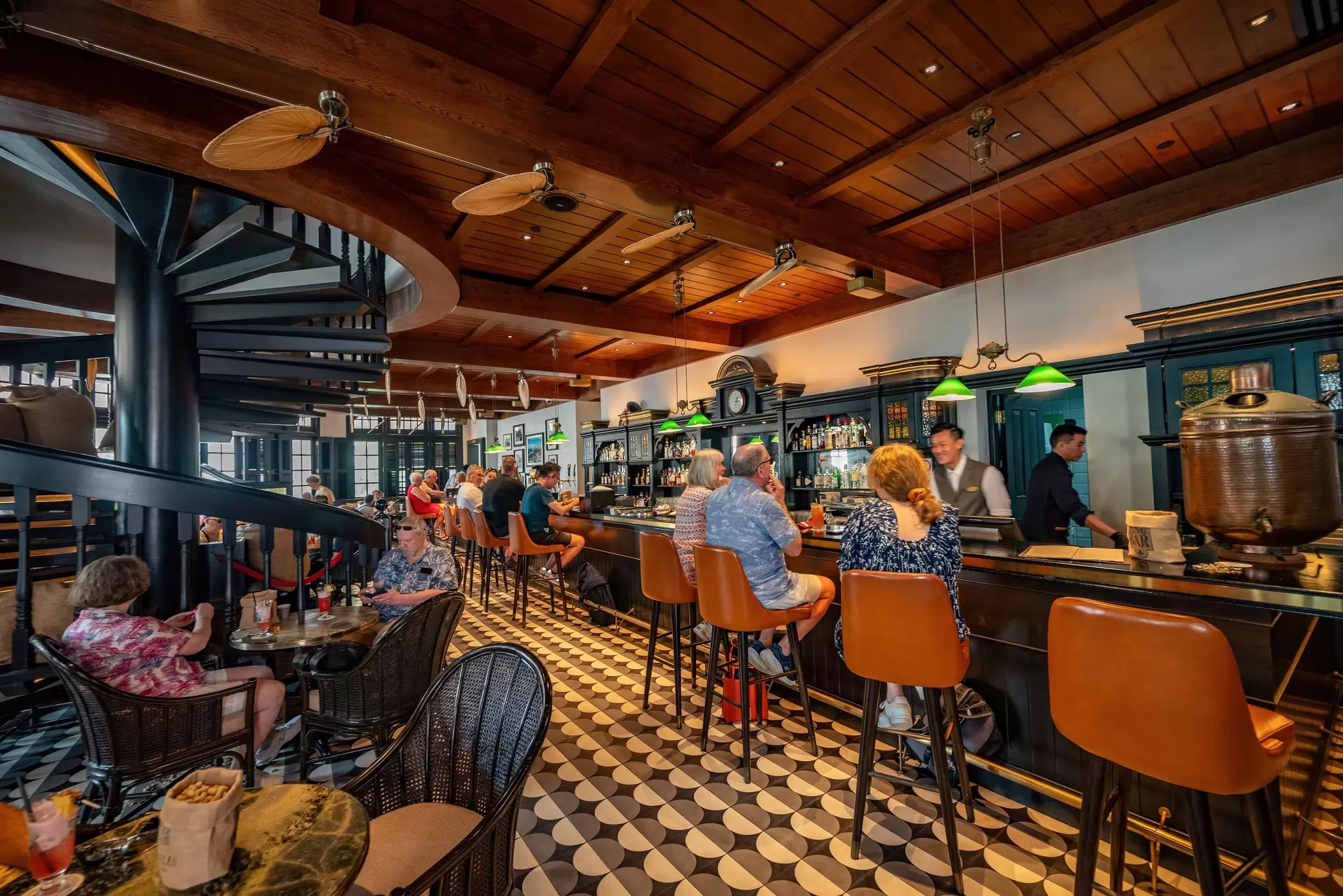 People drinking at the Long Bar in the historic Raffles Singapore hotel.