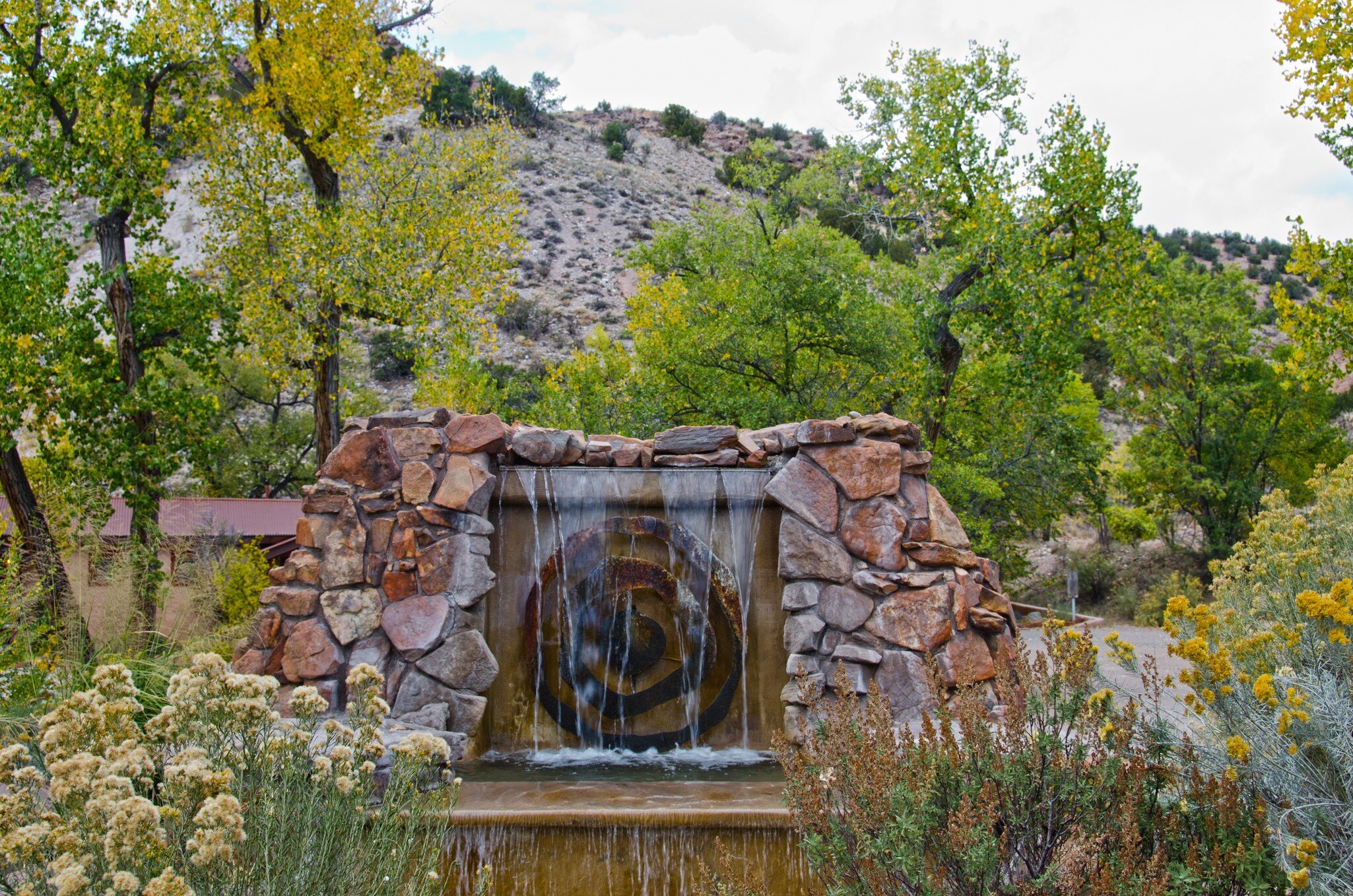 The entrance to Ojo Caliente Hot Springs in New Mexico is marked by a sandstone fountain.  The resort stands between rugged hills and the river for which is is named.  License Type: media  Download Time: 2023-04-14T12:26:51.000Z  User: Norma.PrauseBrewer_LonelyPlanet  Is Editorial: No  purchase_order:
