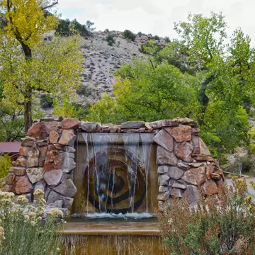 The entrance to Ojo Caliente Hot Springs in New Mexico is marked by a sandstone fountain.  The resort stands between rugged hills and the river for which is is named.  License Type: media  Download Time: 2023-04-14T12:26:51.000Z  User: Norma.PrauseBrewer_LonelyPlanet  Is Editorial: No  purchase_order: