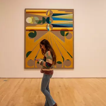 A visitor walking past a painting at a modern art museum in San Francisco