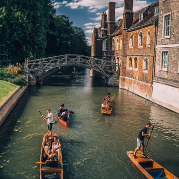 Cambridge, UK - August 20, 2017 : People punting in a canal next to the Mathematical bridge  License Type: media  Download Time: 2022-05-26T15:42:56.000Z  User: clairenaylor  Is Editorial: Yes  purchase_order:   