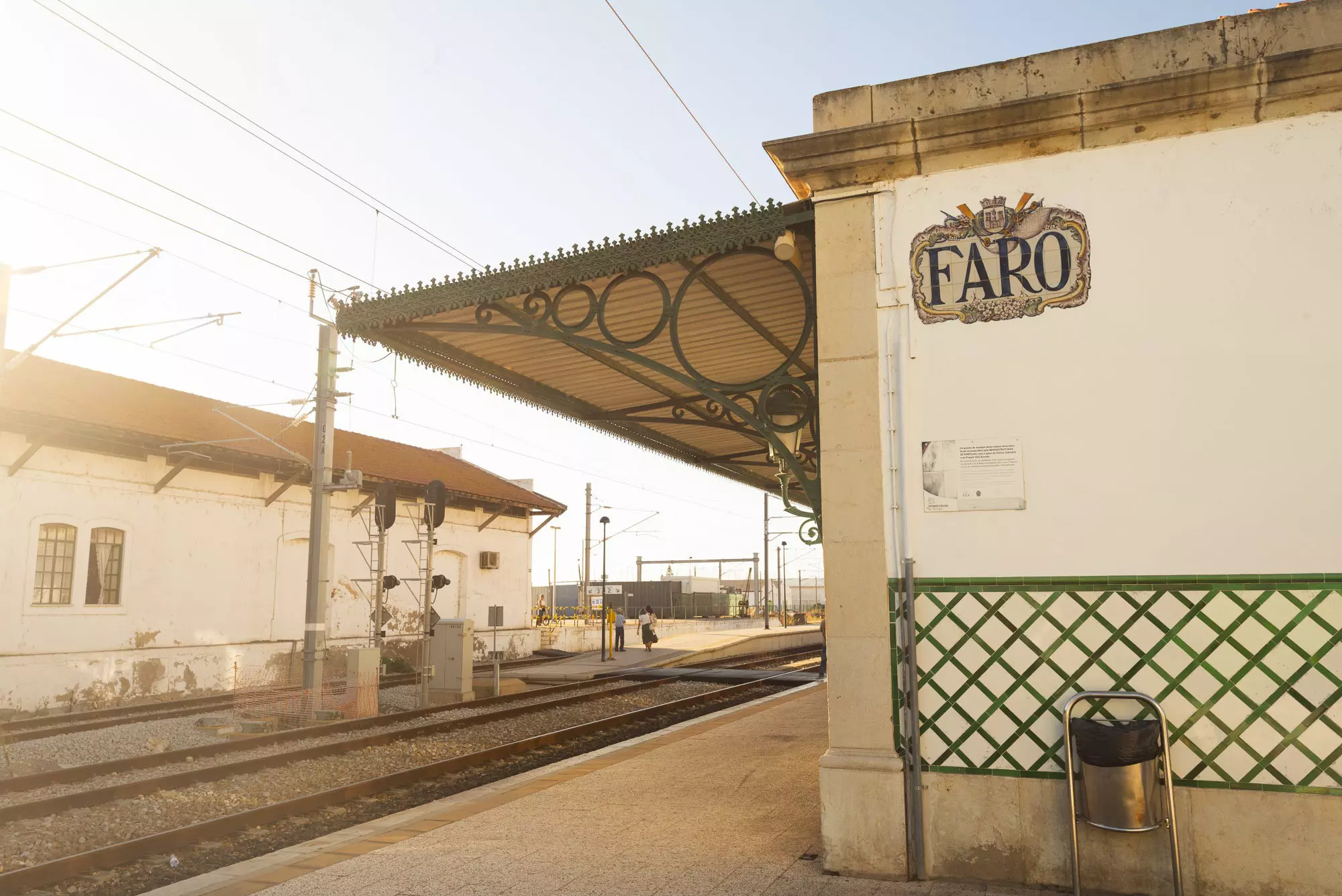 A train station with a decorative awning over the platform and a tile sign that says "Faro".