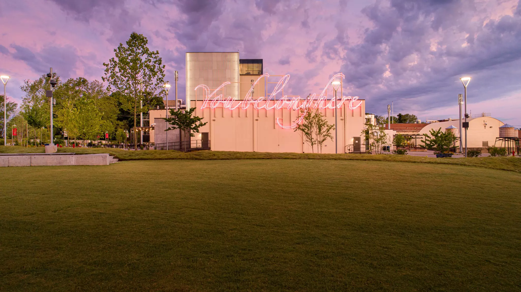 A building at dusk with a neon light that says "you belong here."