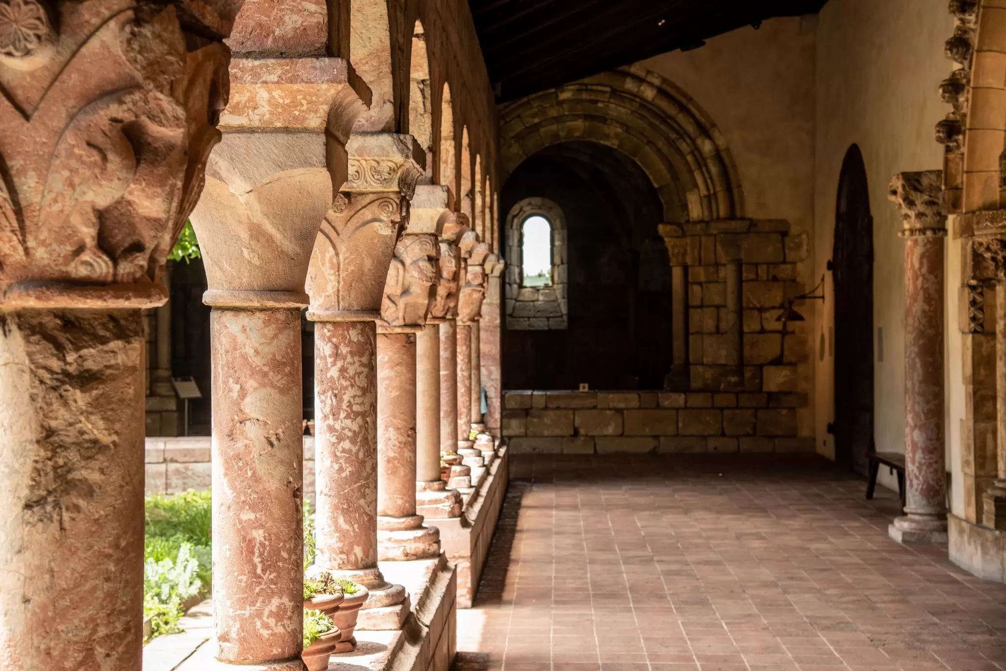 a covered stone walkway in a medieval cloister lined with columns