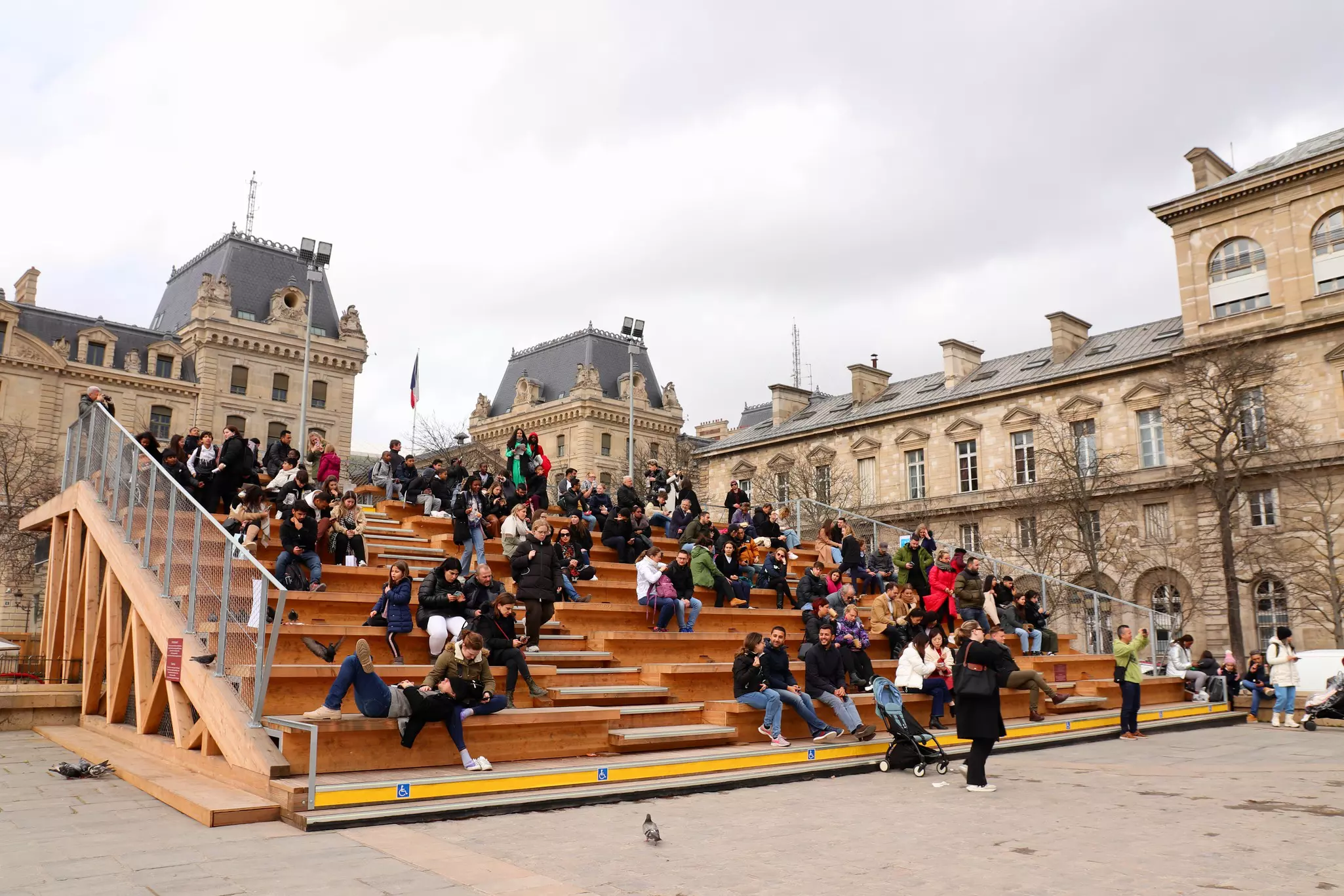 People sit on bleachers in a historic area of Paris.