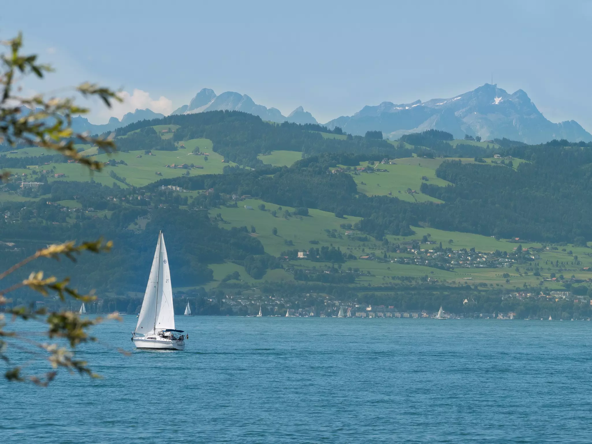 A small sailboat on a lake overlooked by vast mountains