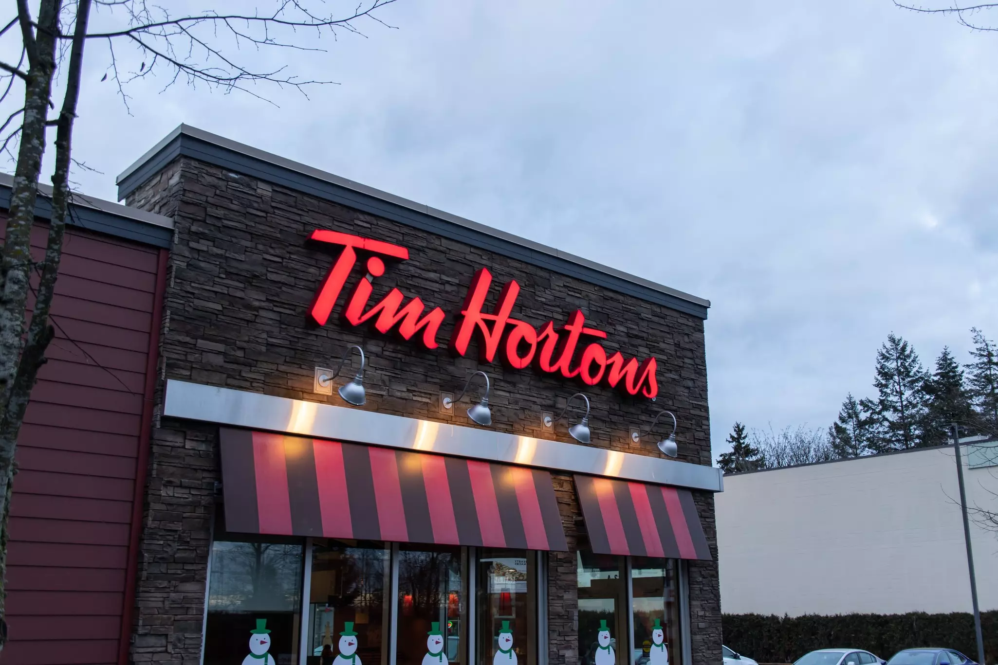Exterior of Tim Hortons with decorative snowmen decals on the windows.