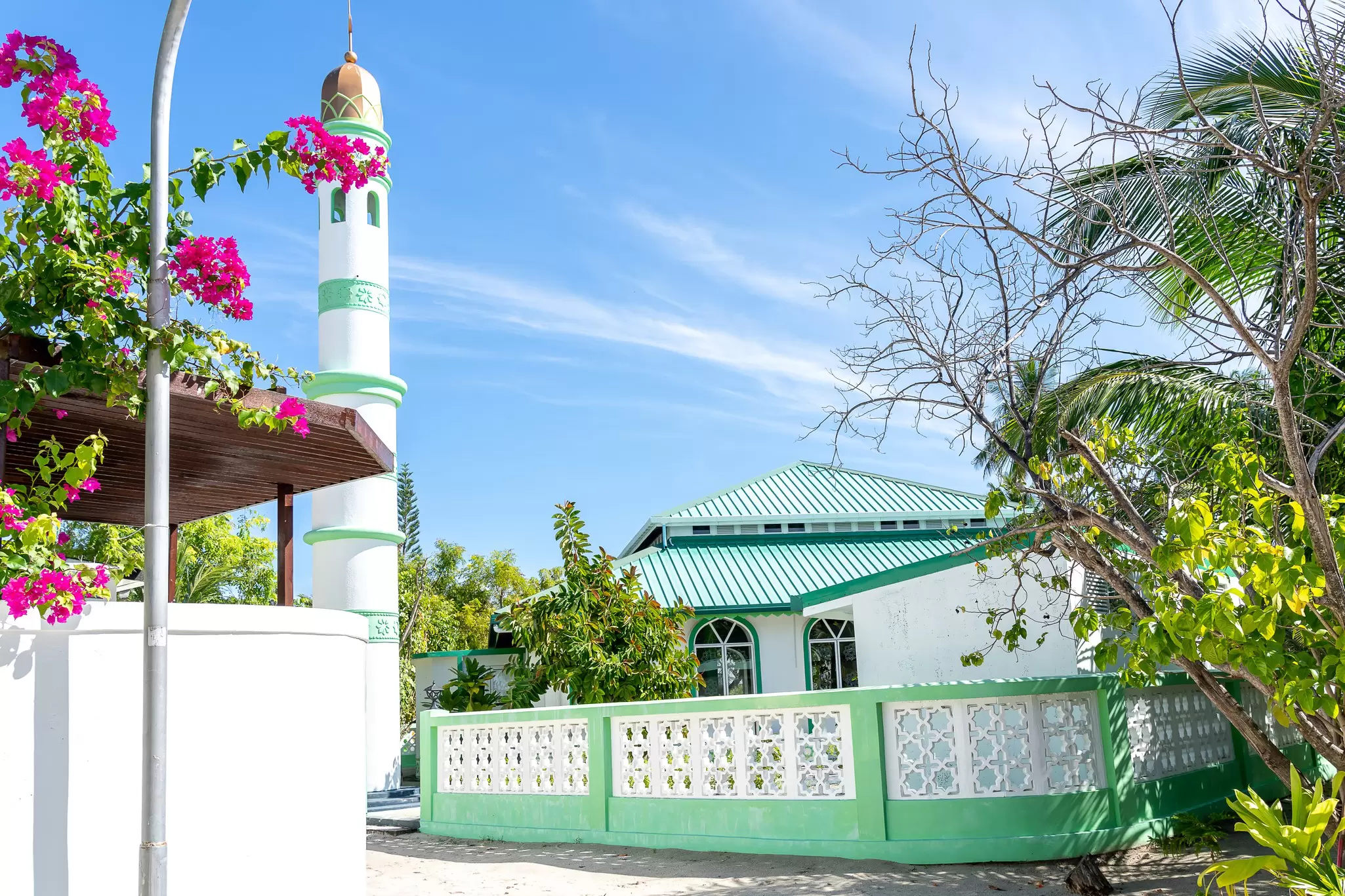 A white and green mosque with a tall minaret in Fulidhoo, the Maldives
