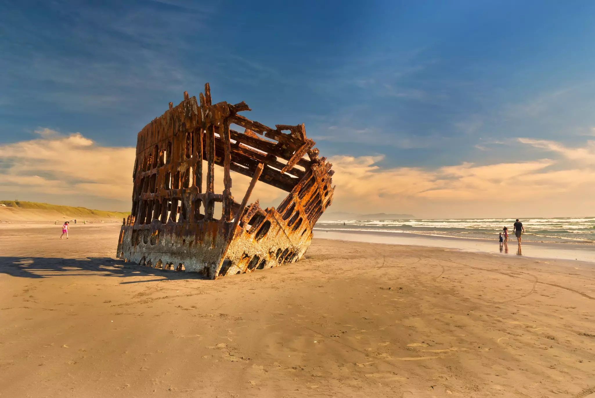 The eroded metal hull of a shipwreck on golden sands
