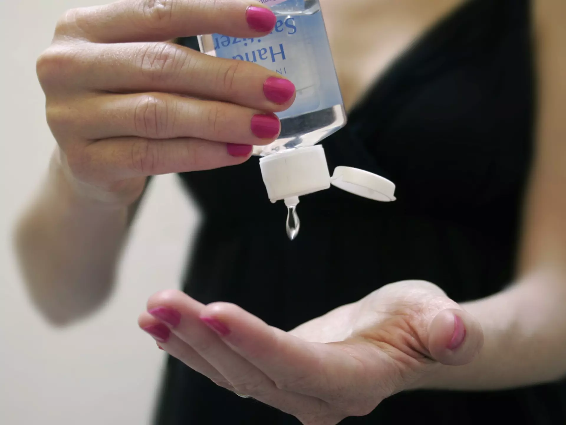 A woman's hands squeezing the lemon wedge into her cocktail