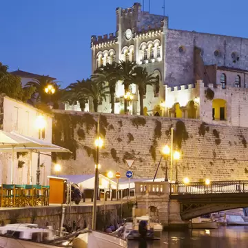 Nighttime view across the water of the Museu Municipal in the Ciutadella of Menorca, Spain.