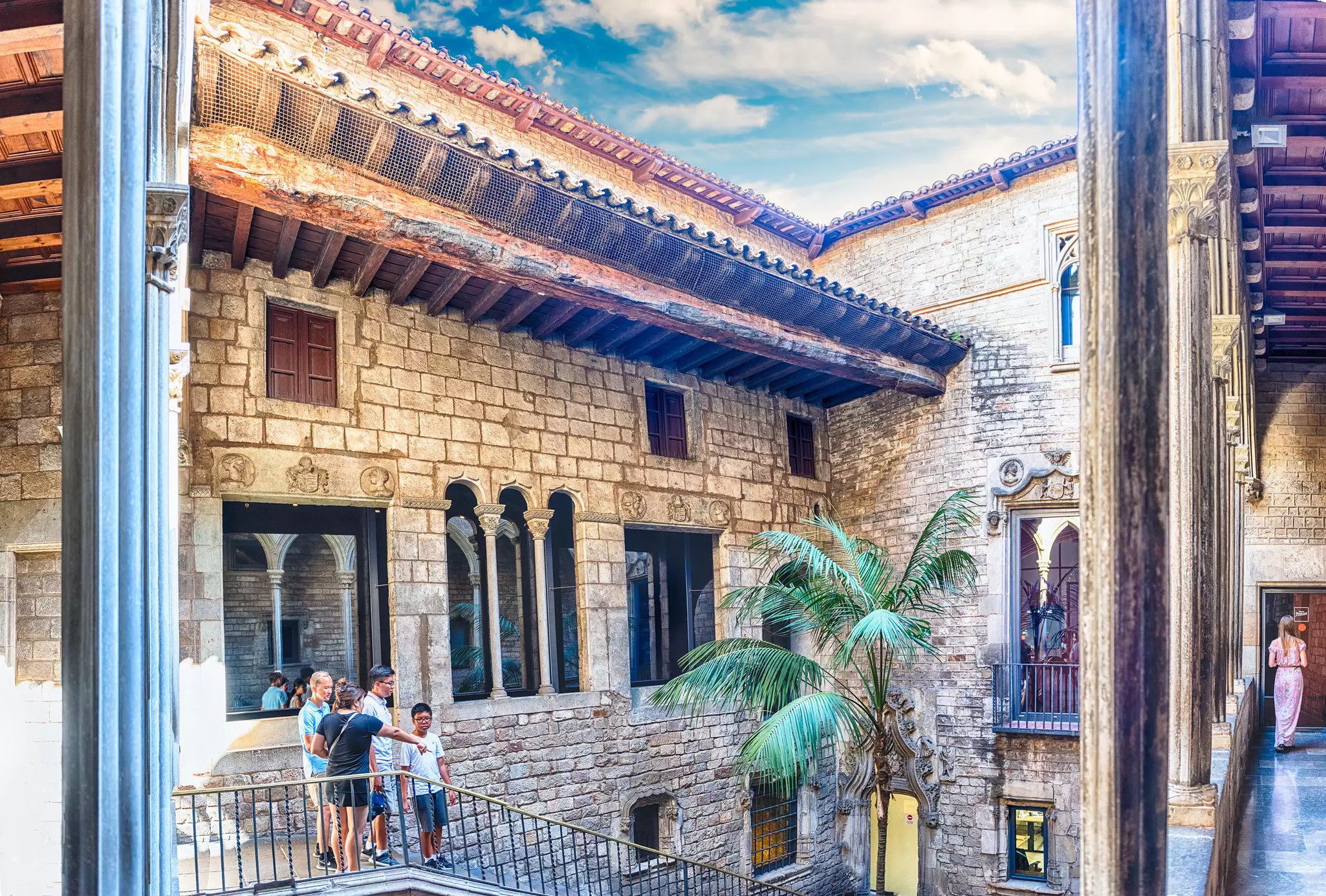 The inner courtyard of Museu Picasso. The square courtyard is spacious, and people walk down a staircase and into it.