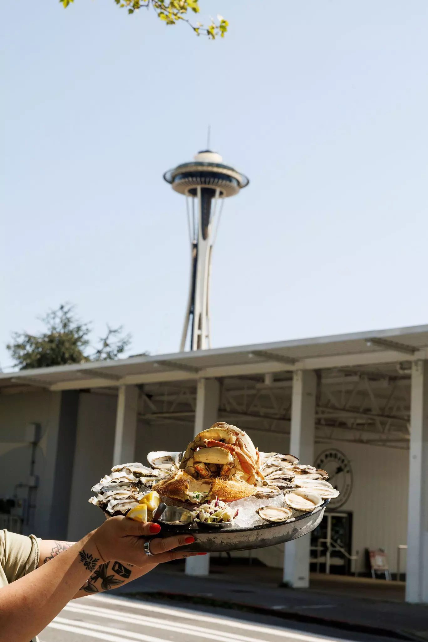 Hands holding a large serving plate of oysters