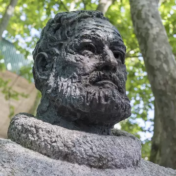 A statue of a bearded man under trees.