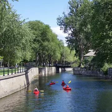 Lachine, Montrel, Canada. July 2021. Man kayaking in the Lachine canal water scenic view of environmental friendly suburbia rich in green trees