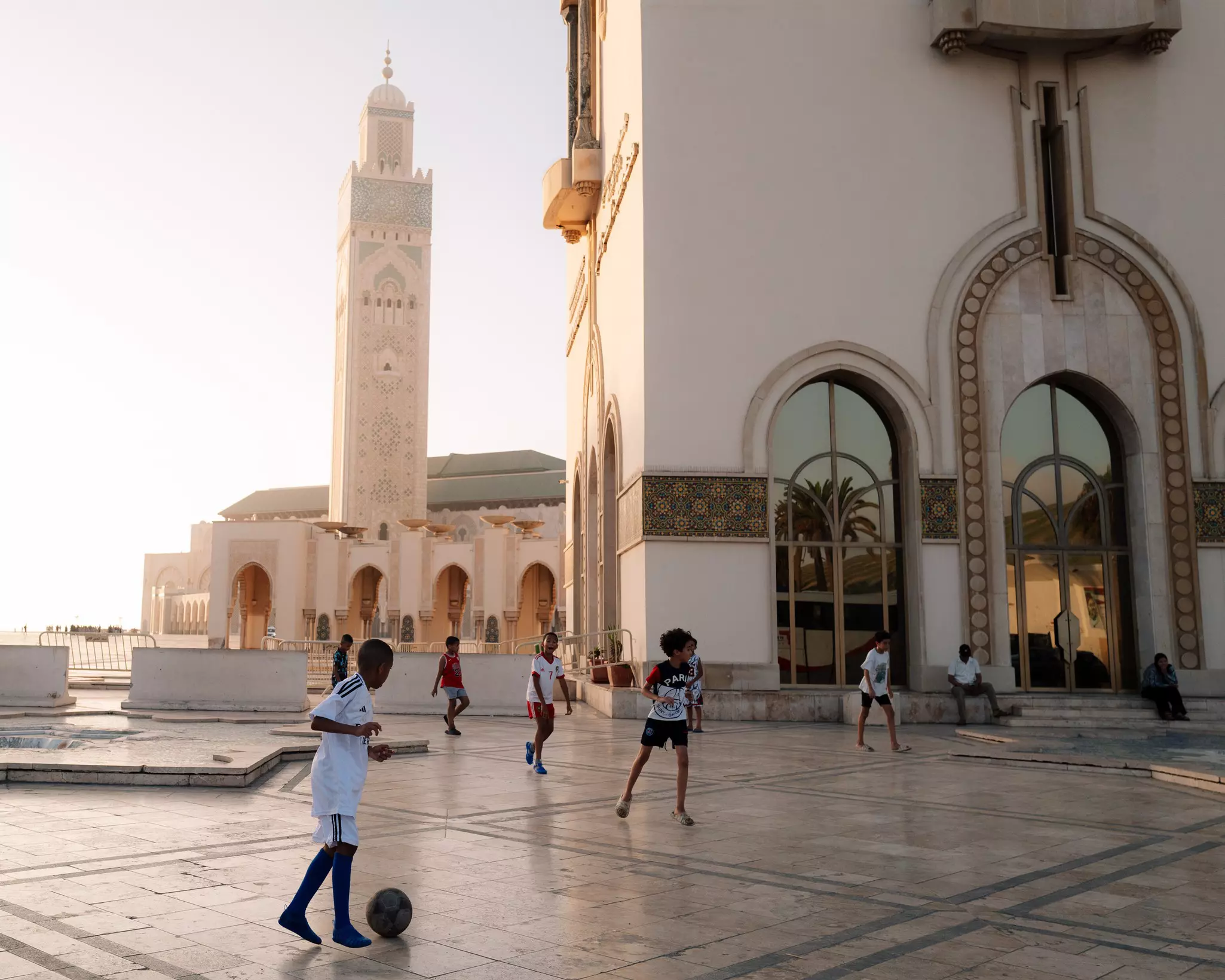 Children playing soccer in front of the Hassan II Mosque in Casablanca, Morocco.