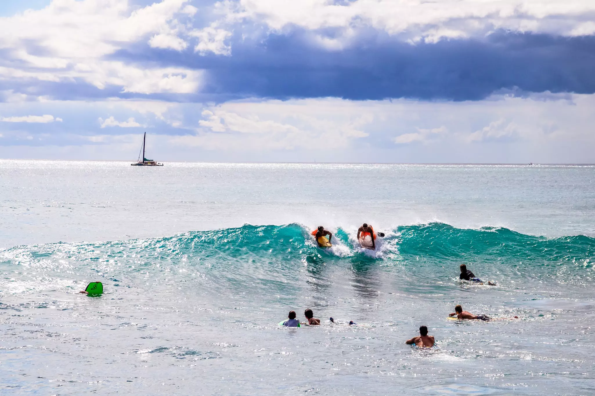Waikiki, Oahu, Hawaii: people on vacation having fun swimming on boogie board at Queens Surf Beach, a section of Waikiki Beach in Honolulu.