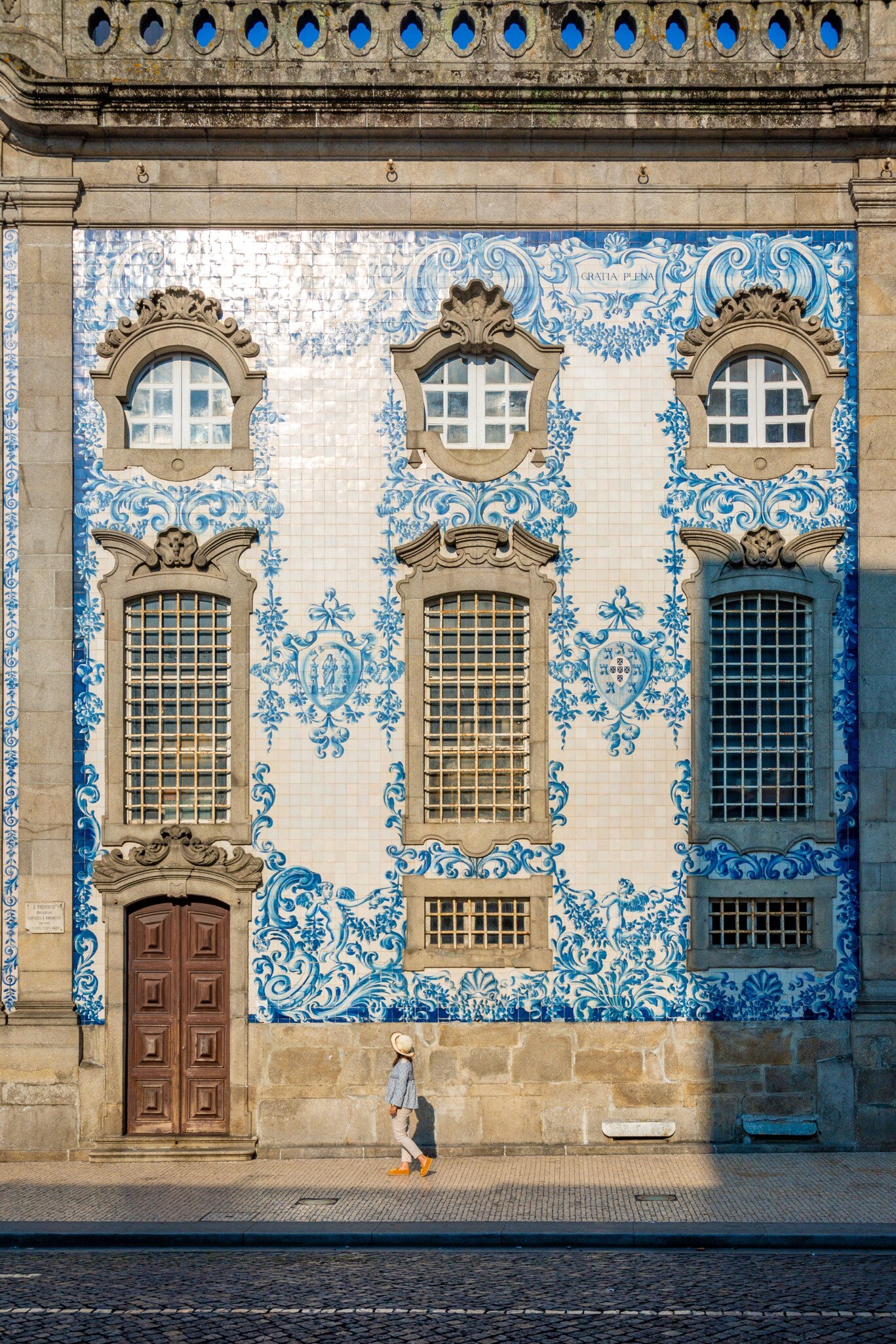 A group of people having a conversation on the street in front of a wall of tiles in Porto, Portugal.