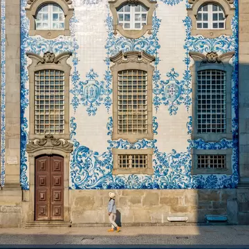 A group of people having a conversation on the street in front of a wall of tiles in Porto, Portugal.