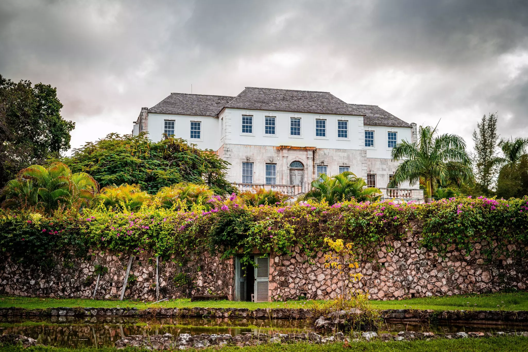Rose Hall Great House with pink flowers in the foreground and gray skies above