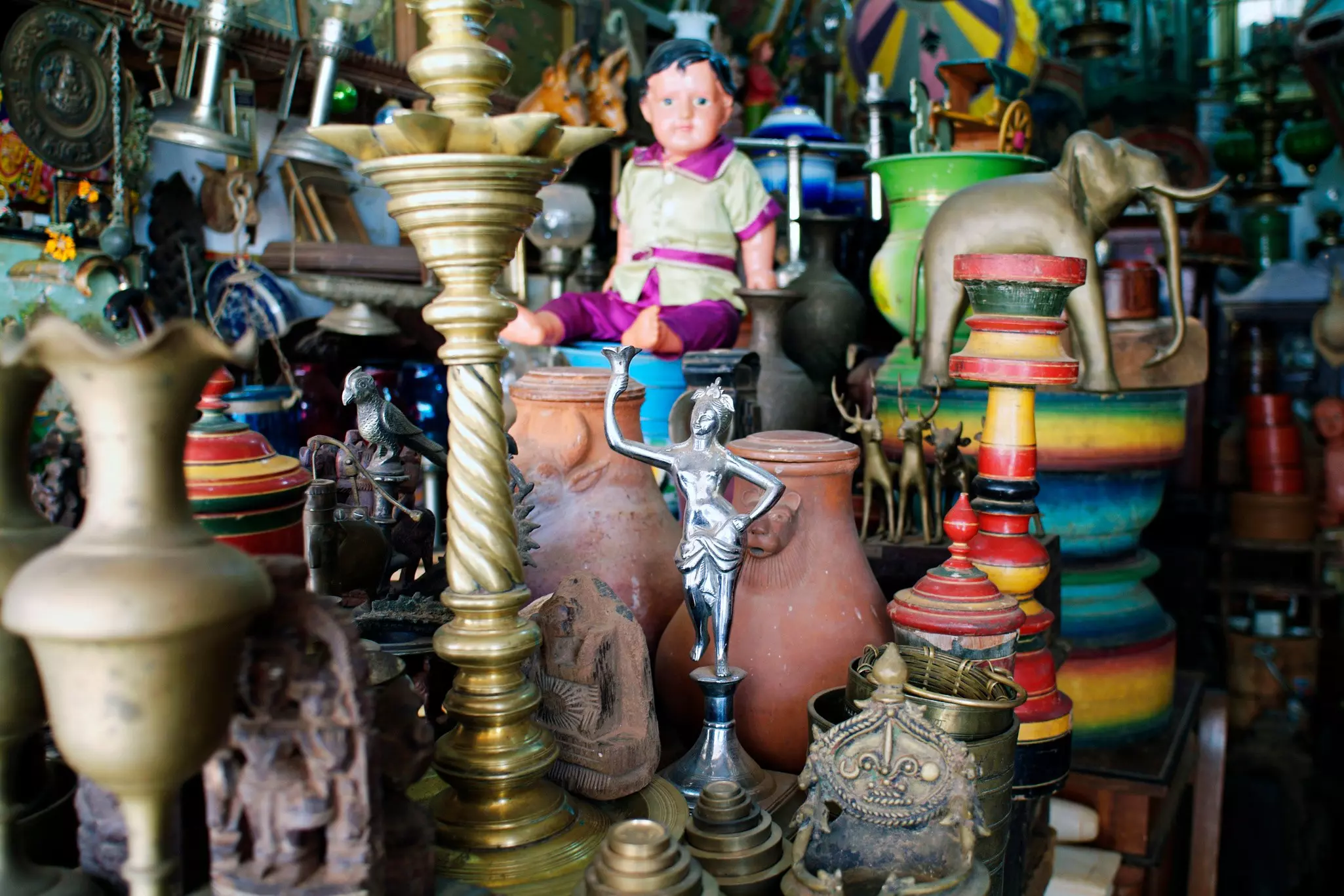 Objects including statues, candlesticks and pots are clustered at an antiques market.