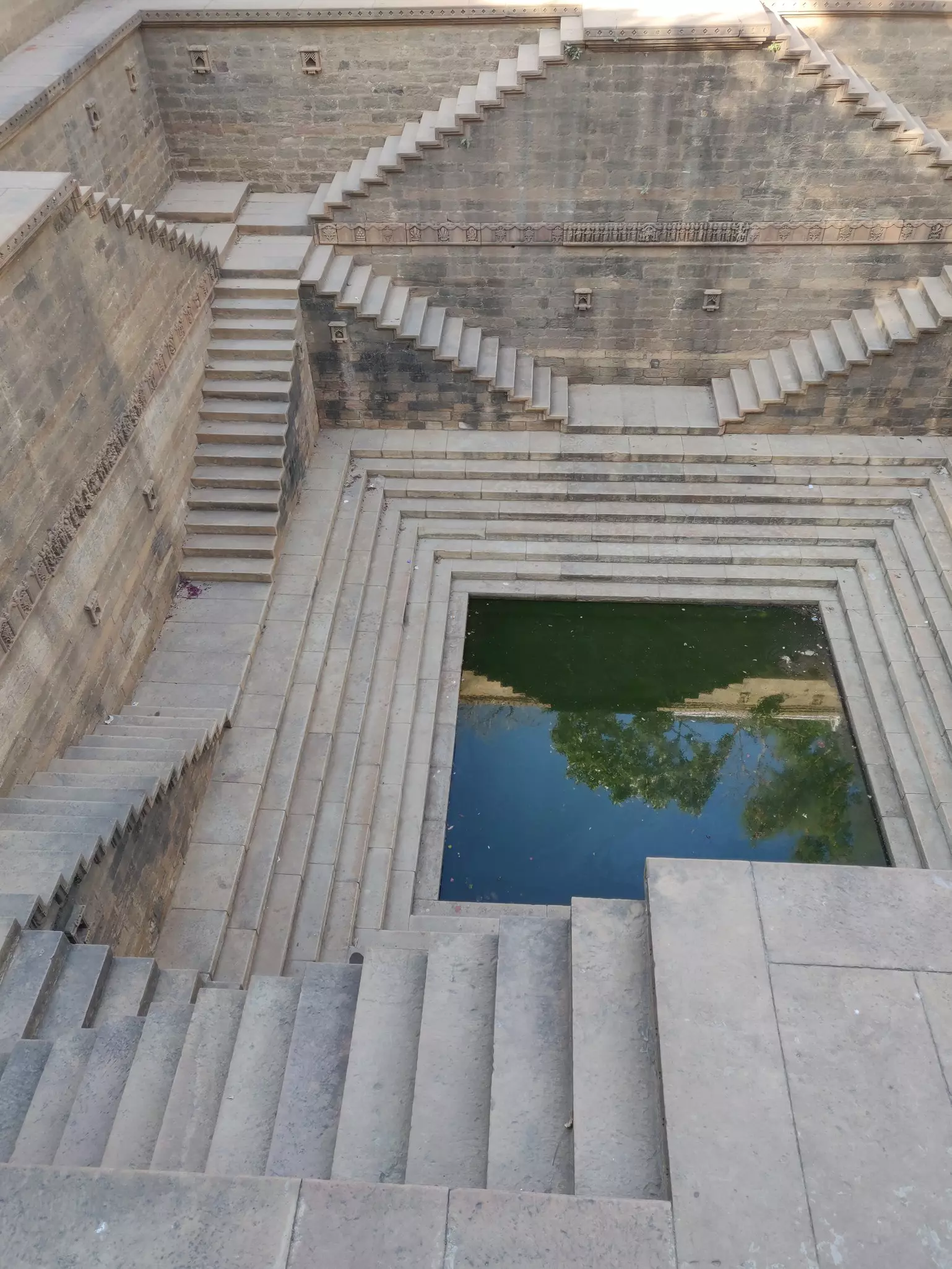 A square well with perfect geometrical steps heading down from all angles to the water 