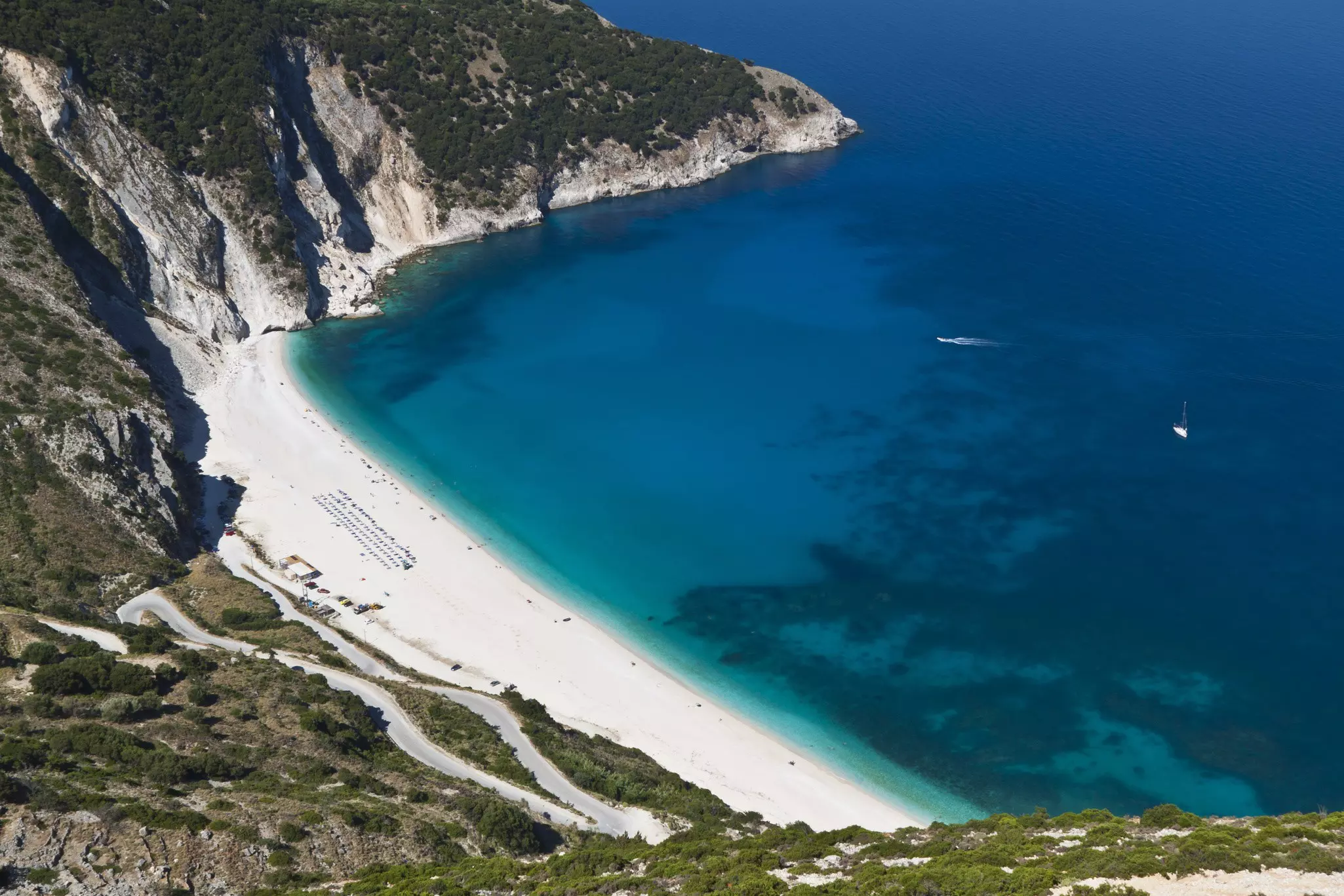 Aerial shot of a white-sand beach surrounded by dramatic cliffs.