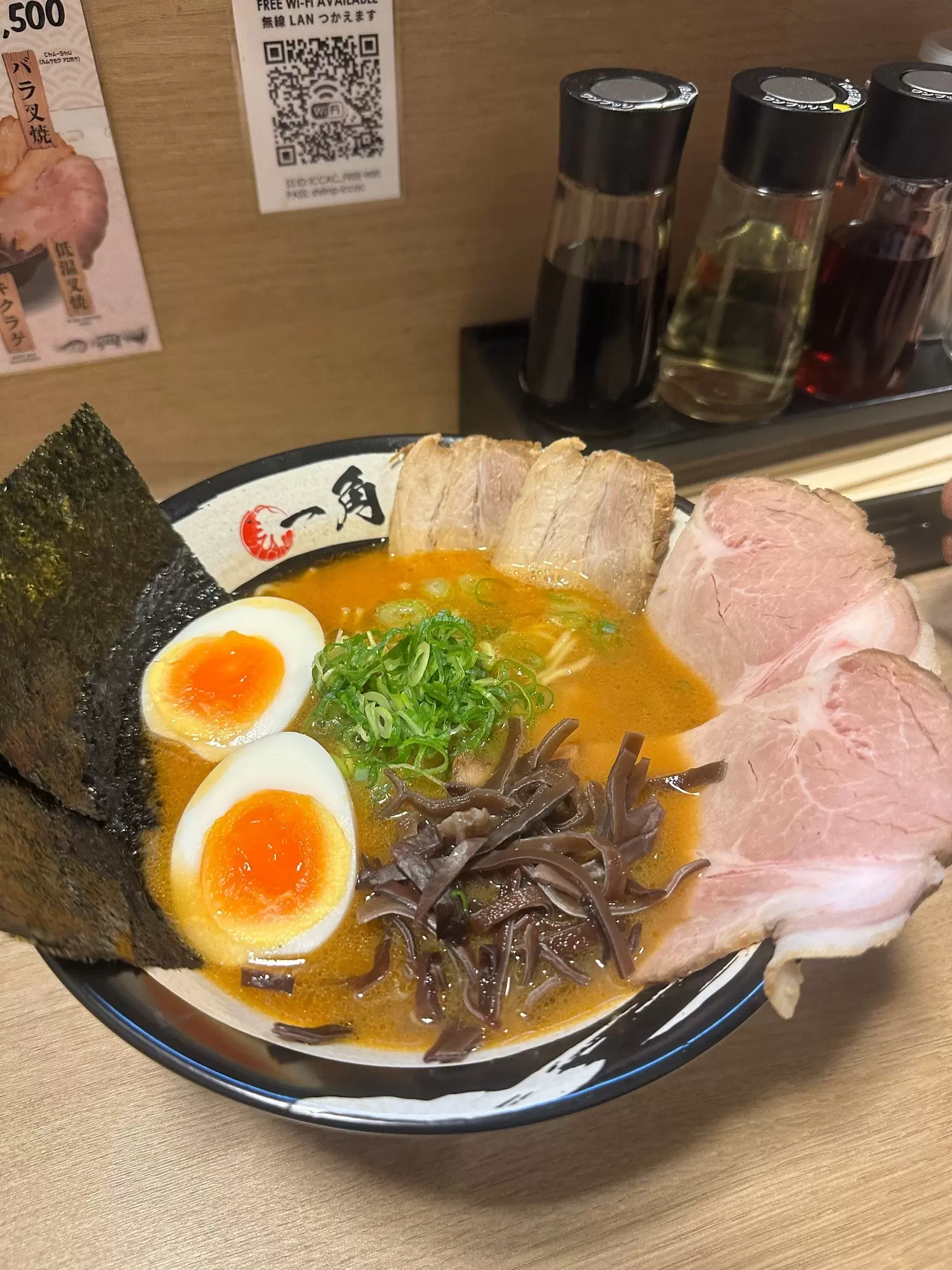 A bowl of broth with noodles, meat, egg and vegetables around the side or floating on top: Shrimp miso-rāmen from Shrimp Ramen ICCAC in Ganso Ramen Yokocho