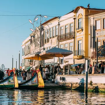 Colorful traditional boat docked in Aveiro, Portugal with vibrant architecture in the background.