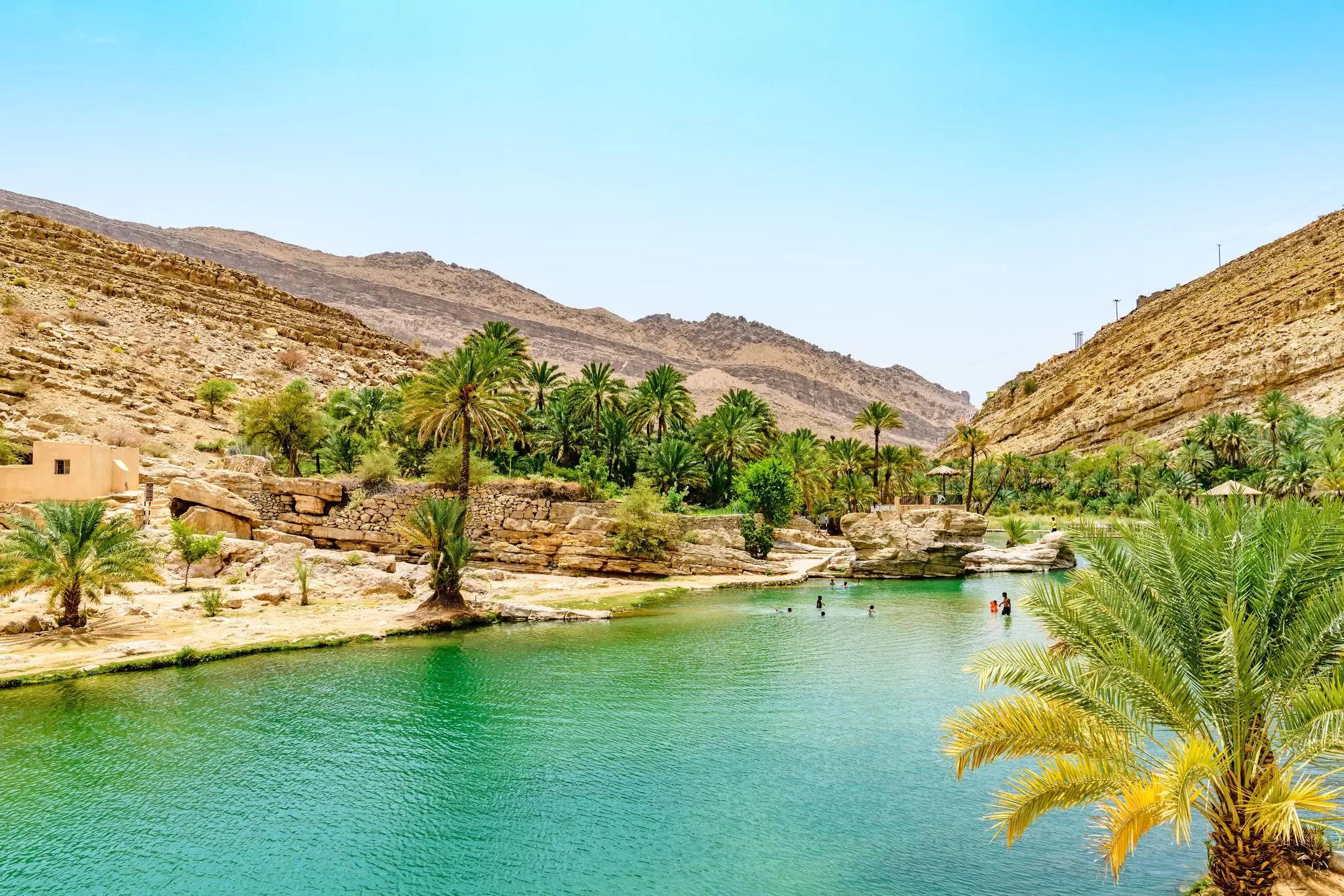 Swimmers in a ravine at an oasis in a desert area: Wadi Bani Khalid, Oman 