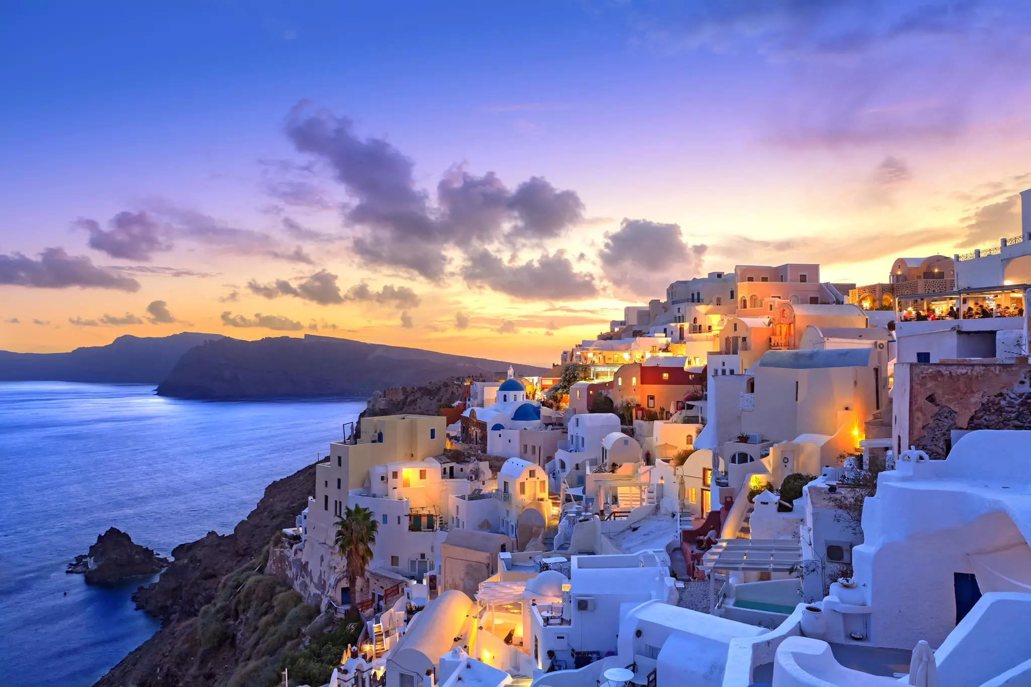 Santorini sunset at village of Oia Greece with some lights on in houses